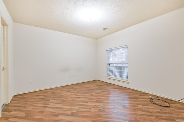 unfurnished room with light hardwood / wood-style floors and a textured ceiling