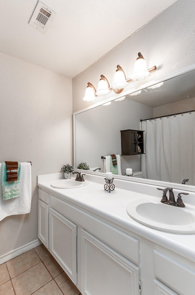 bathroom featuring double vanity, visible vents, a sink, and tile patterned floors