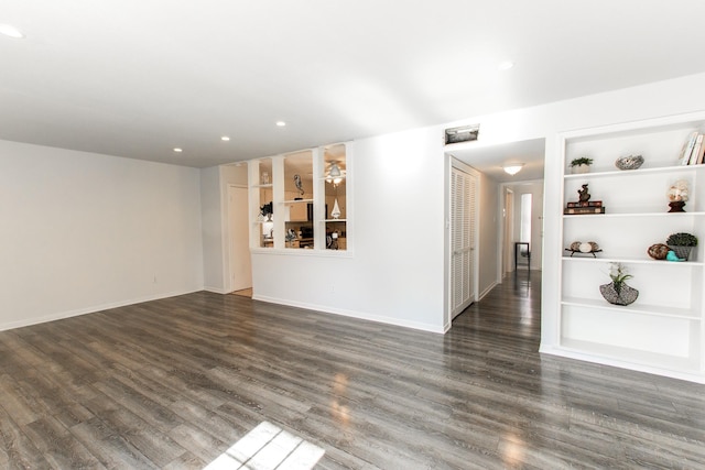 spare room with baseboards, recessed lighting, dark wood finished floors, and built in features