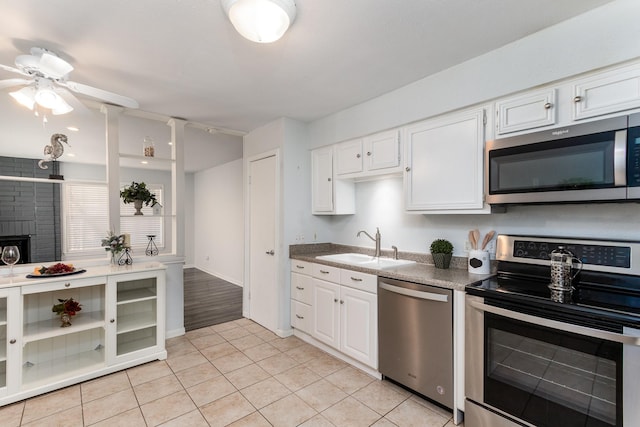 kitchen with light tile patterned floors, a sink, white cabinetry, a ceiling fan, and appliances with stainless steel finishes