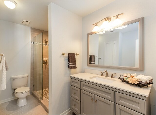 bathroom with vanity, a shower with door, and toilet