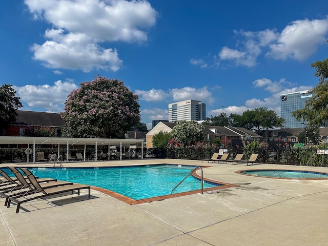 community pool featuring a patio area, a hot tub, and fence