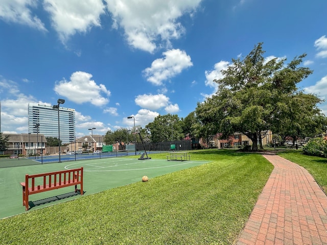 view of property's community with a tennis court, a yard, and fence