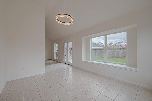 empty room featuring french doors, vaulted ceiling, and light tile patterned floors