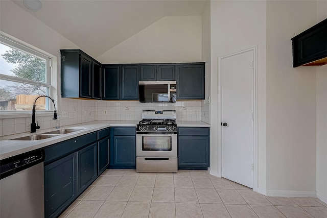 kitchen featuring appliances with stainless steel finishes, sink, light tile patterned floors, and decorative backsplash