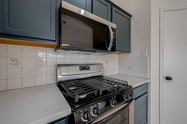 kitchen with stainless steel appliances, tasteful backsplash, and blue cabinetry