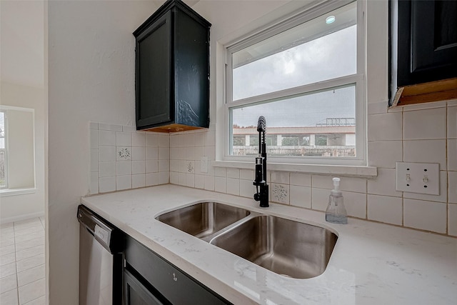 kitchen with tasteful backsplash, light stone countertops, sink, and stainless steel dishwasher