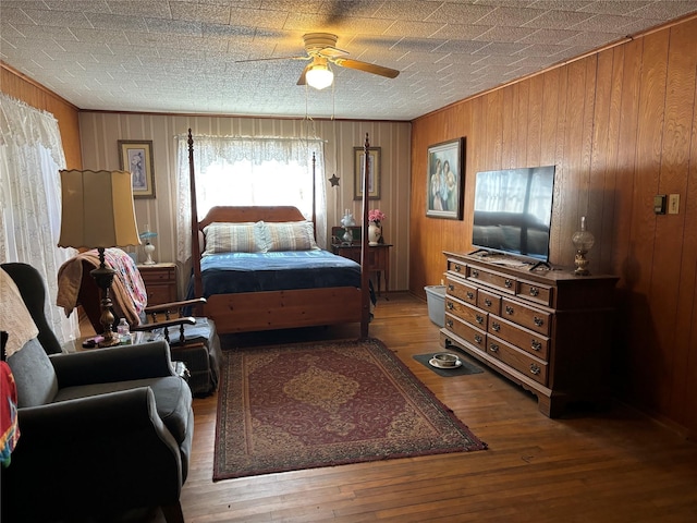 bedroom featuring hardwood / wood-style floors, ceiling fan, and wood walls