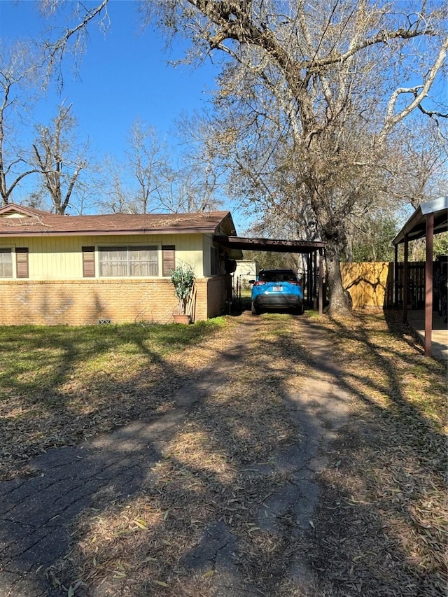 504 E Bell Ave, Crockett, TX 75835 - view of property exterior with fence, brick siding, a carport, and dirt driveway