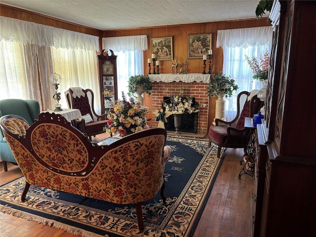 living room with dark wood-type flooring, wooden walls, and a brick fireplace