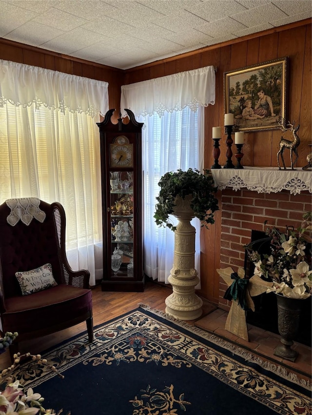 sitting room featuring wood-type flooring, a fireplace, and wood walls