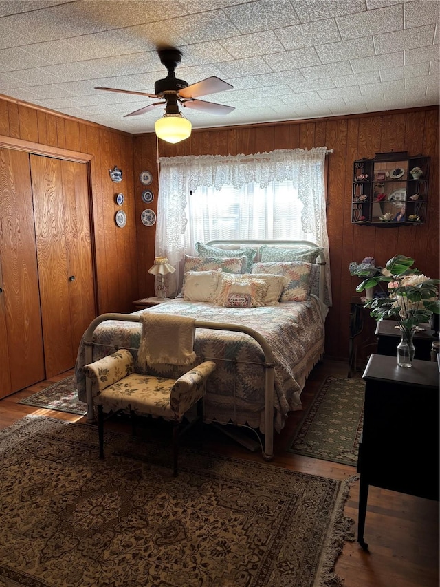 bedroom featuring ceiling fan and wood walls