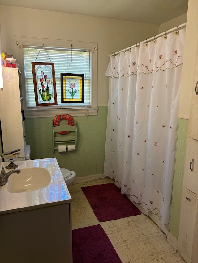 504 E Bell Ave, Crockett, TX 75835 - full bathroom featuring tile patterned floors, toilet, wainscoting, tile walls, and vanity