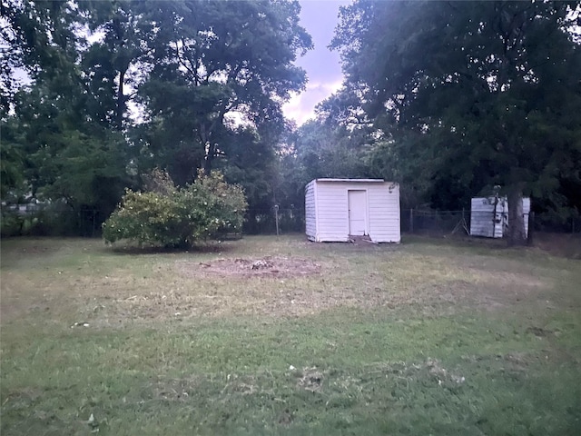 504 E Bell Ave, Crockett, TX 75835 - yard at dusk featuring a shed, an outbuilding, and a lawn