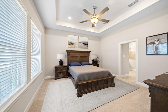 carpeted bedroom featuring visible vents, a raised ceiling, baseboards, and a ceiling fan