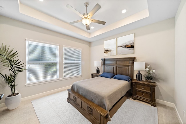 carpeted bedroom with a raised ceiling, recessed lighting, baseboards, and ceiling fan