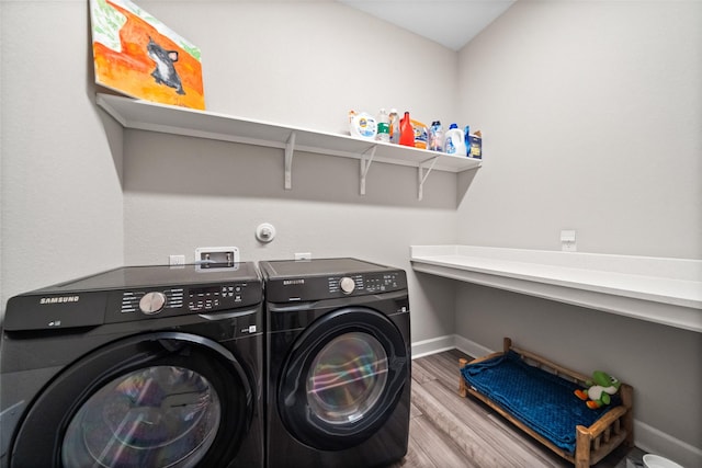 laundry room with laundry area, wood finished floors, baseboards, and washing machine and clothes dryer