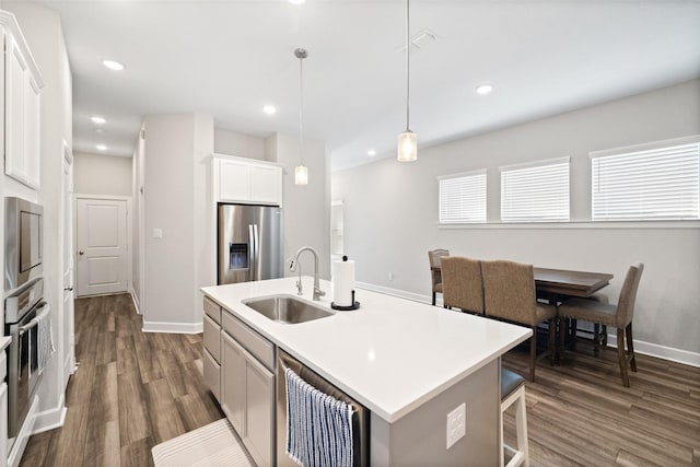 kitchen with a center island with sink, visible vents, a sink, dark wood-type flooring, and appliances with stainless steel finishes