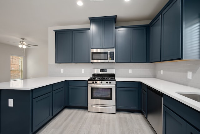 kitchen with decorative backsplash, light hardwood / wood-style flooring, kitchen peninsula, and appliances with stainless steel finishes