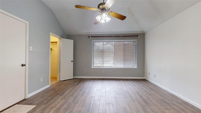 unfurnished bedroom featuring lofted ceiling, light wood-style flooring, a spacious closet, and baseboards