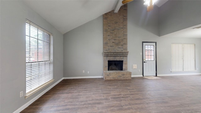 unfurnished living room with a wealth of natural light, a brick fireplace, baseboards, and wood finished floors