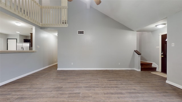 empty room featuring high vaulted ceiling, wood finished floors, a ceiling fan, baseboards, and stairway