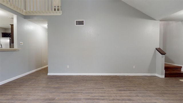 empty room featuring high vaulted ceiling, baseboards, visible vents, and wood finished floors