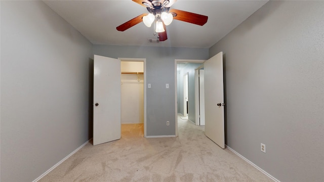 unfurnished bedroom with light colored carpet, visible vents, baseboards, a closet, and a walk in closet