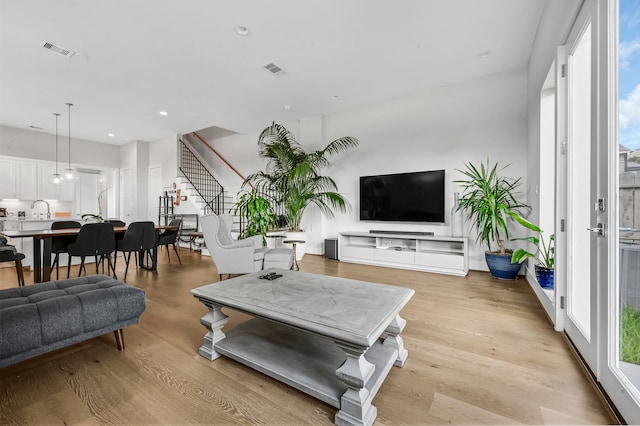 living room featuring sink, light wood-type flooring, and a wealth of natural light