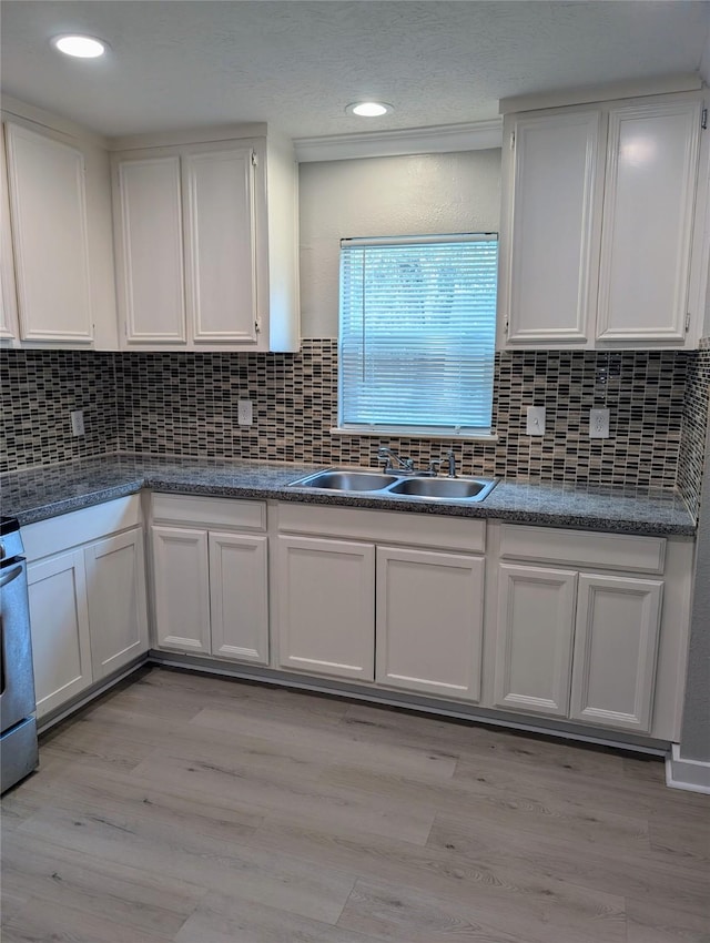 kitchen featuring sink, backsplash, light hardwood / wood-style floors, and white cabinets