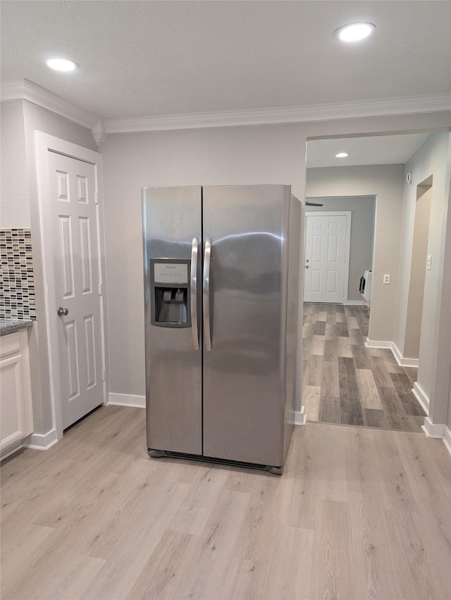 kitchen with stainless steel refrigerator with ice dispenser, crown molding, tasteful backsplash, light hardwood / wood-style floors, and white cabinets