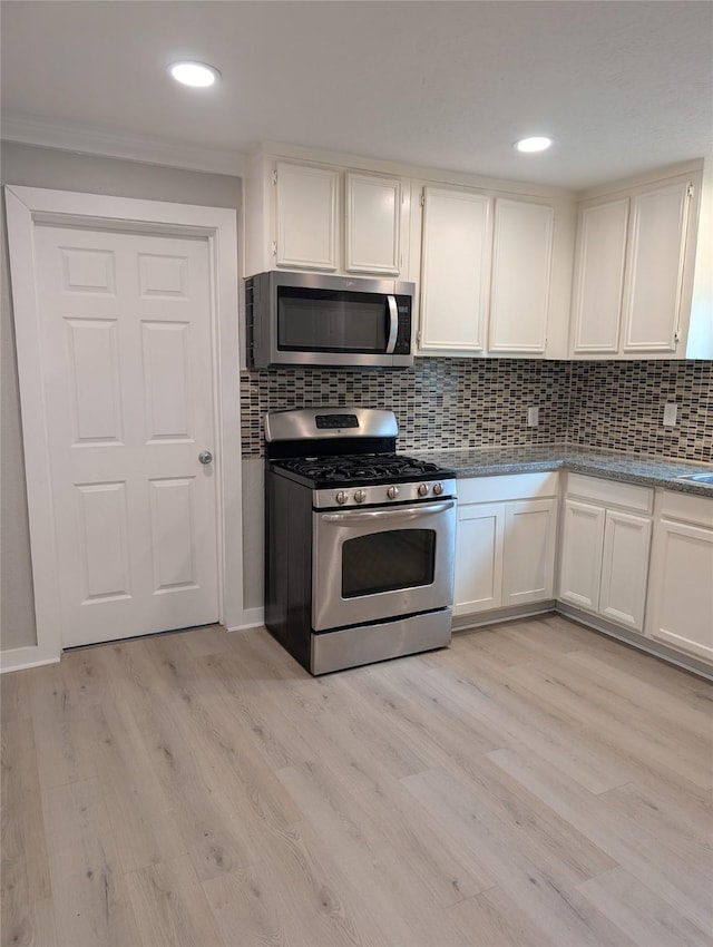 kitchen with light wood-type flooring, white cabinets, and appliances with stainless steel finishes