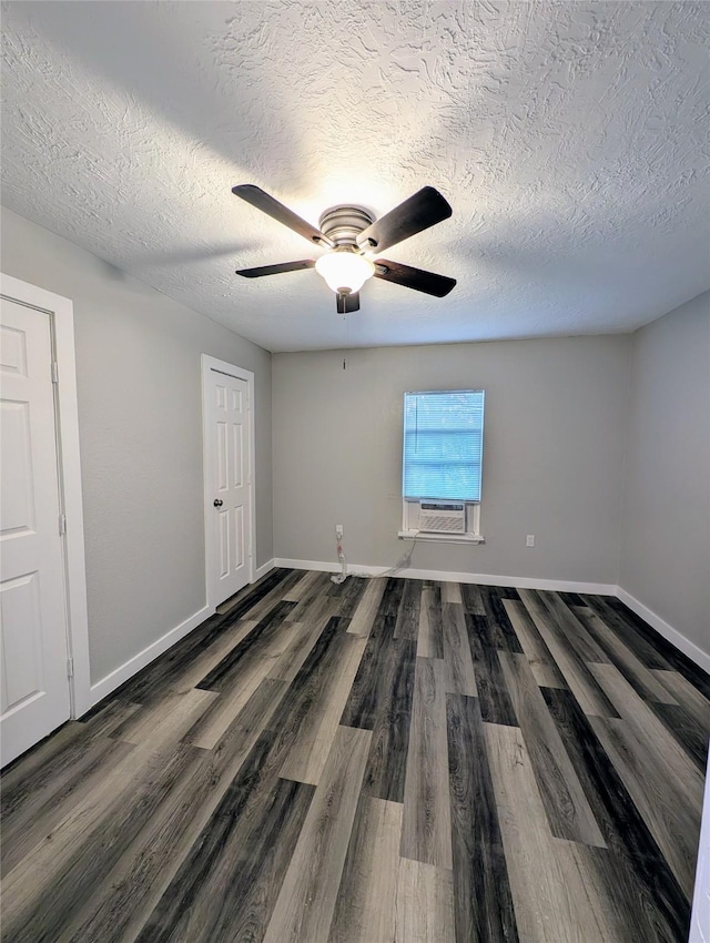 spare room with cooling unit, ceiling fan, dark wood-type flooring, and a textured ceiling