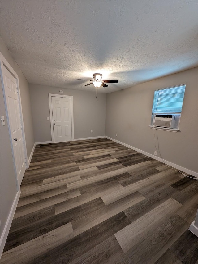 empty room featuring ceiling fan, dark wood-type flooring, cooling unit, and a textured ceiling