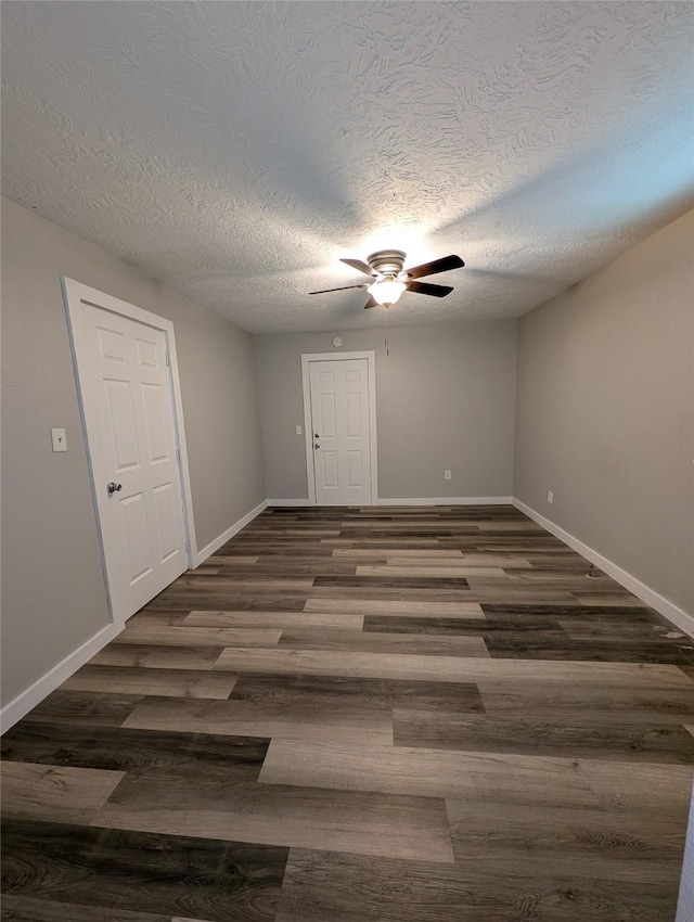 empty room with ceiling fan, dark hardwood / wood-style floors, and a textured ceiling