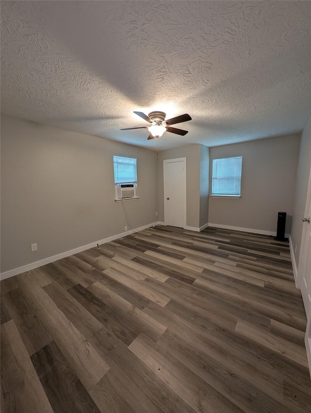 empty room featuring dark wood-type flooring, a wealth of natural light, and cooling unit