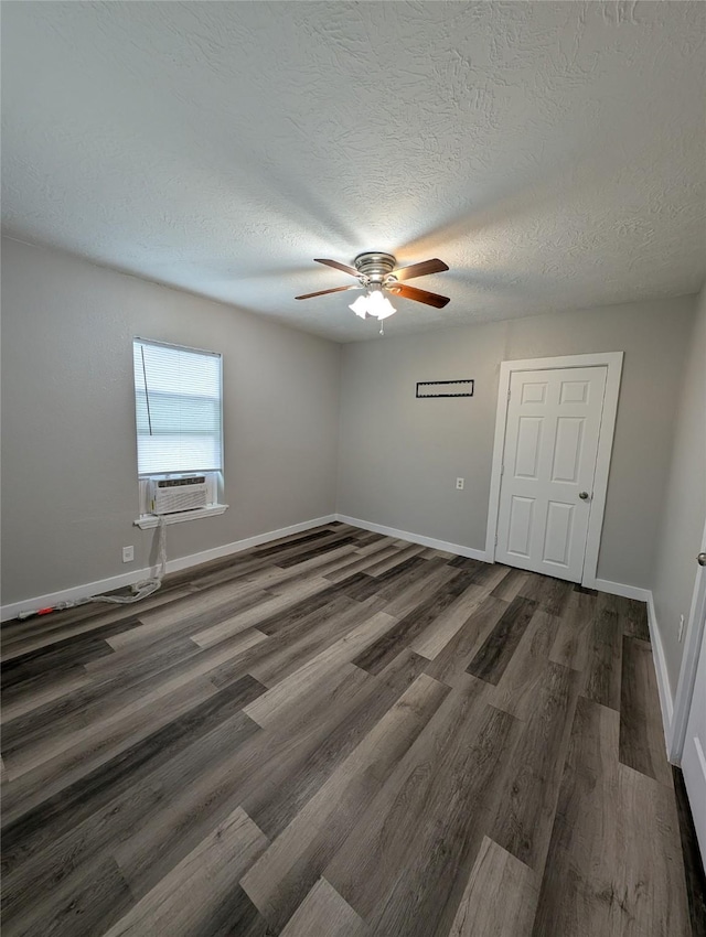 empty room with dark wood-type flooring, ceiling fan, cooling unit, and a textured ceiling