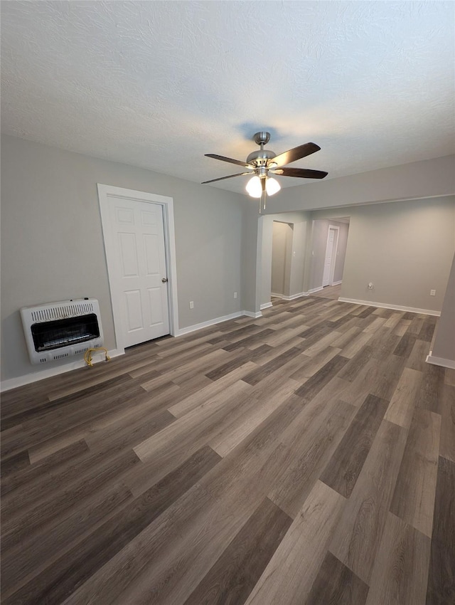 unfurnished living room with dark hardwood / wood-style floors, heating unit, a textured ceiling, and ceiling fan