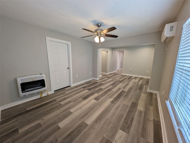 unfurnished living room with heating unit, a textured ceiling, an AC wall unit, hardwood / wood-style flooring, and ceiling fan