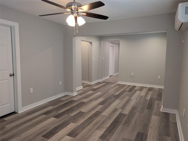 spare room featuring a textured ceiling, dark wood-type flooring, a wall unit AC, and ceiling fan