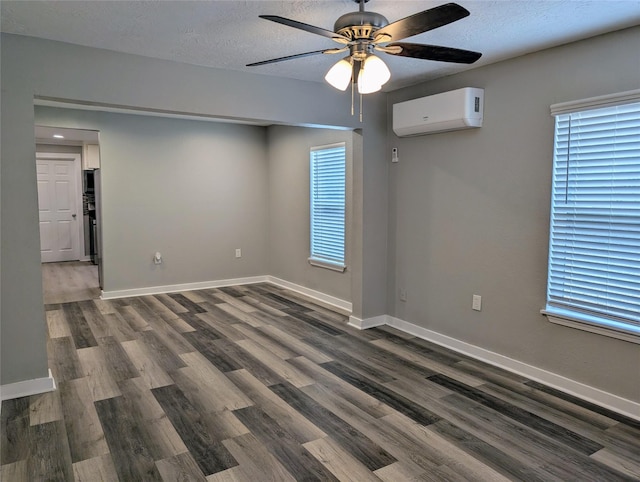 spare room with dark hardwood / wood-style flooring, plenty of natural light, a textured ceiling, and a wall unit AC