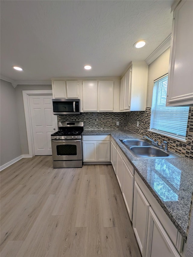 kitchen with white cabinetry, sink, light hardwood / wood-style flooring, and appliances with stainless steel finishes