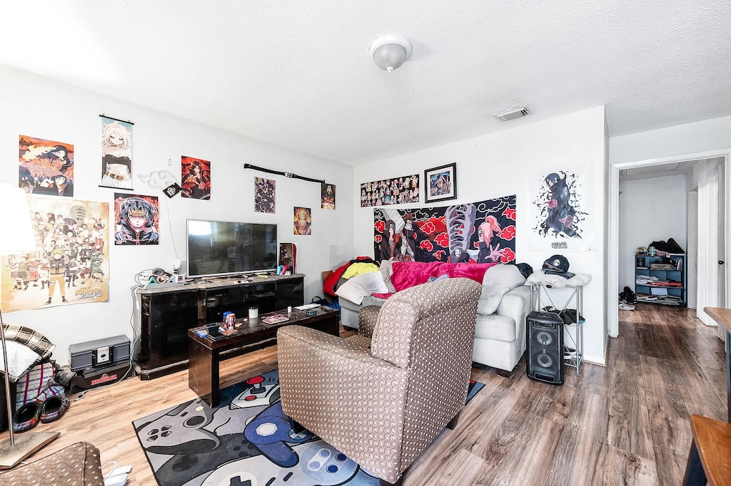 living room featuring wood-type flooring and a textured ceiling