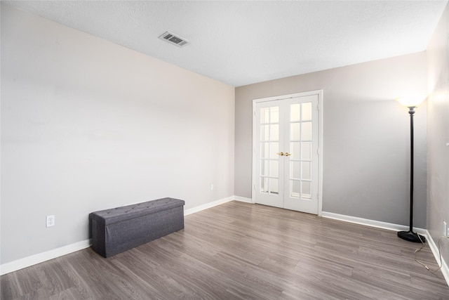 spare room featuring hardwood / wood-style floors, a textured ceiling, and french doors