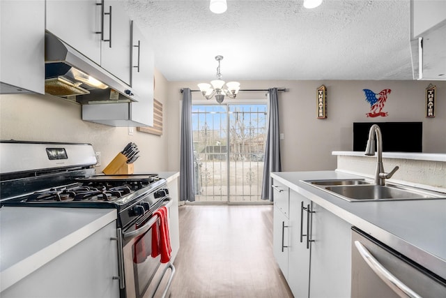 kitchen featuring sink, a textured ceiling, pendant lighting, stainless steel appliances, and white cabinets