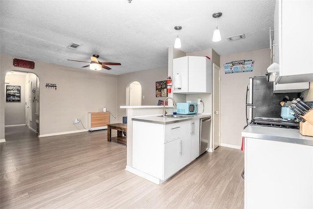 kitchen with pendant lighting, white cabinetry, appliances with stainless steel finishes, and a textured ceiling