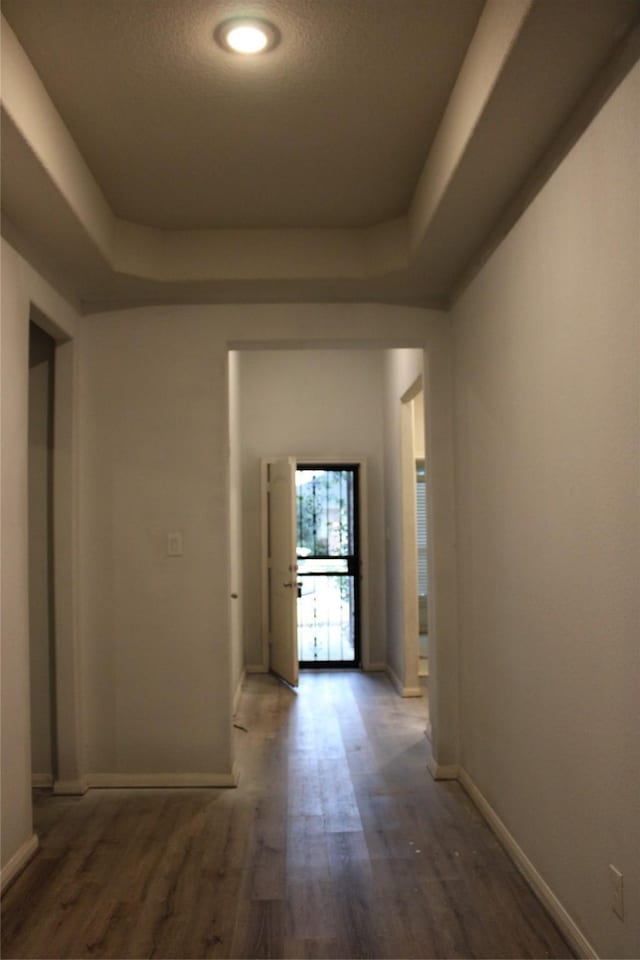 corridor featuring dark hardwood / wood-style floors and a tray ceiling