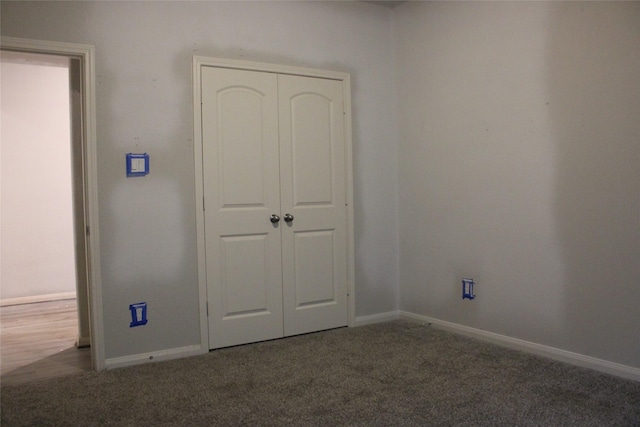 unfurnished bedroom with a closet and dark colored carpet