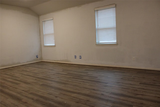 spare room featuring lofted ceiling and dark hardwood / wood-style floors