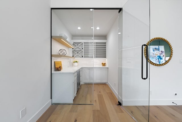 kitchen with white cabinetry, tasteful backsplash, and light hardwood / wood-style flooring